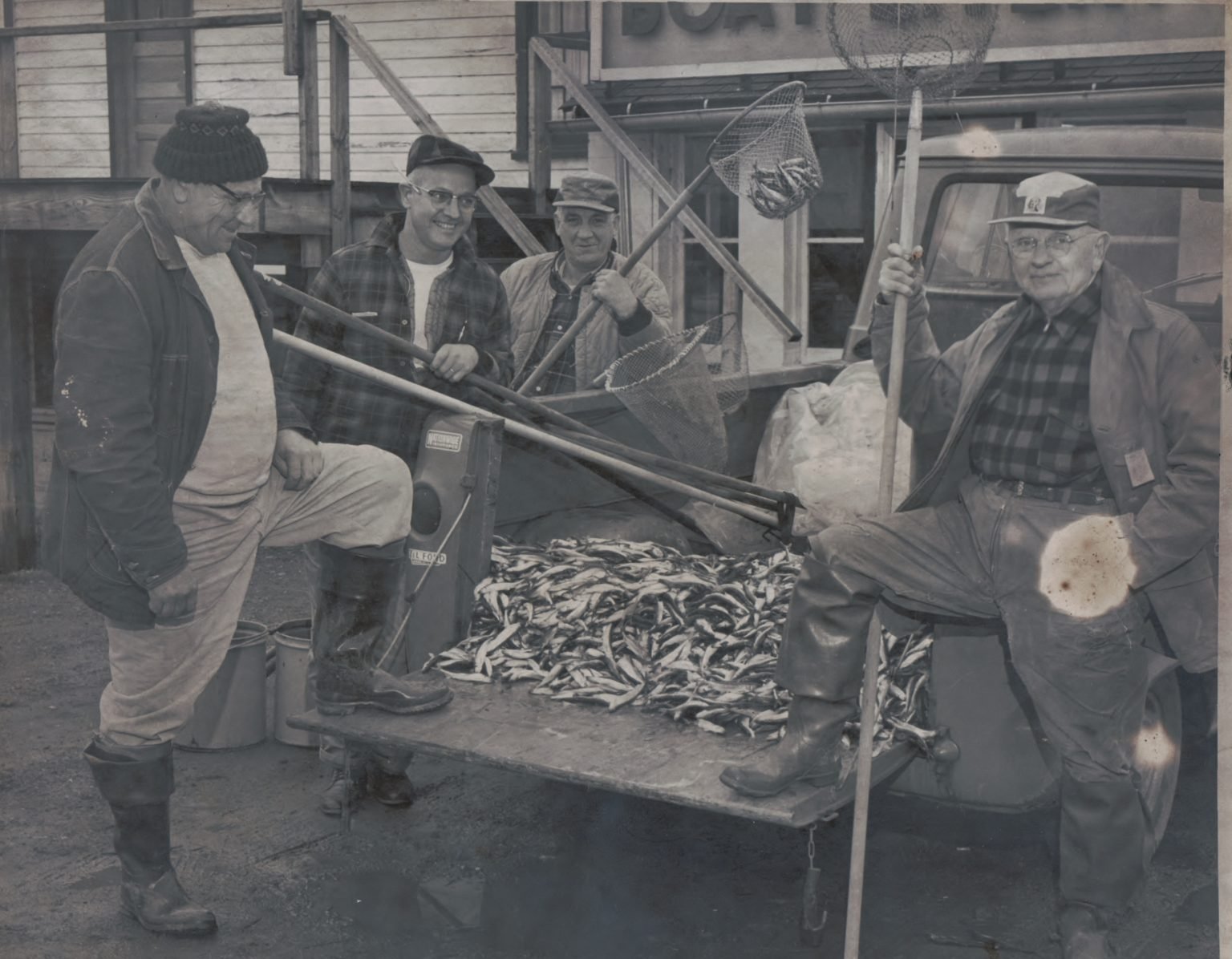 Oscar Fuerst, Bob Chase Sr., John DeVey and Bill Koush with dip nets around a truck tailgate heaped with smelt