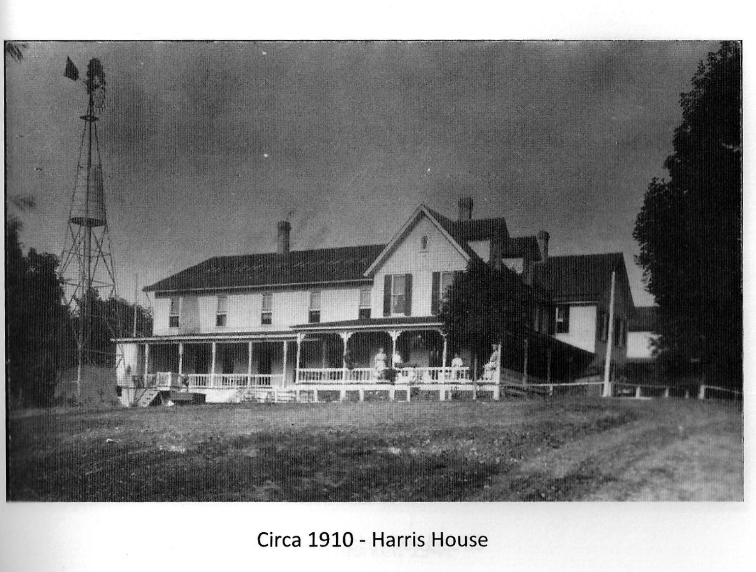 Harris House about 1910: large two-story frame building with a long front porch and a tall windmill beside it
