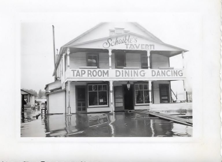 Floodwater in front of Schaible's Tavern, a two-story building signed 'Tap Room Dining Dancing'