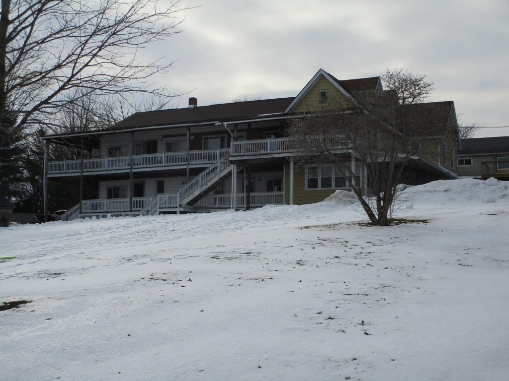 The former Harris House, a long two-story building with double porches and outside stairs, above a snowy lawn