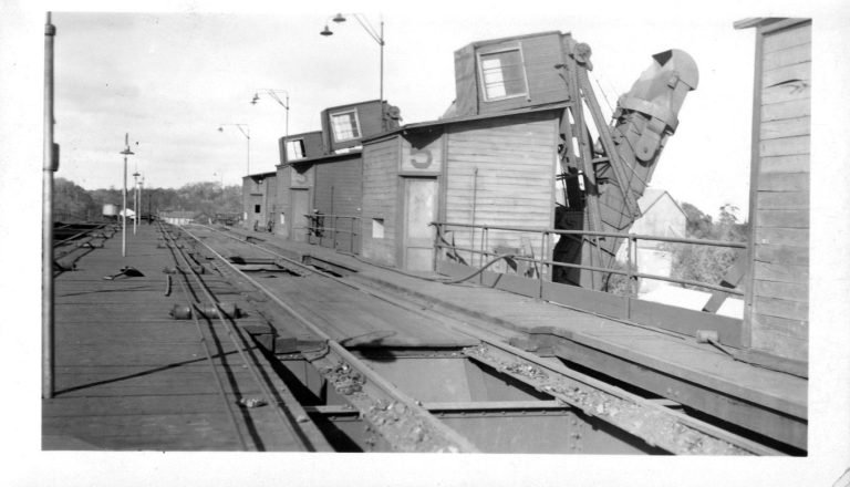 Top deck of the coal trestle: tracks over dumping pits beside wooden operator shacks and a loading chute