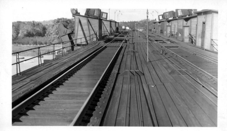 Long view down the plank deck and tracks atop the coal trestle, wooden shacks lining both sides