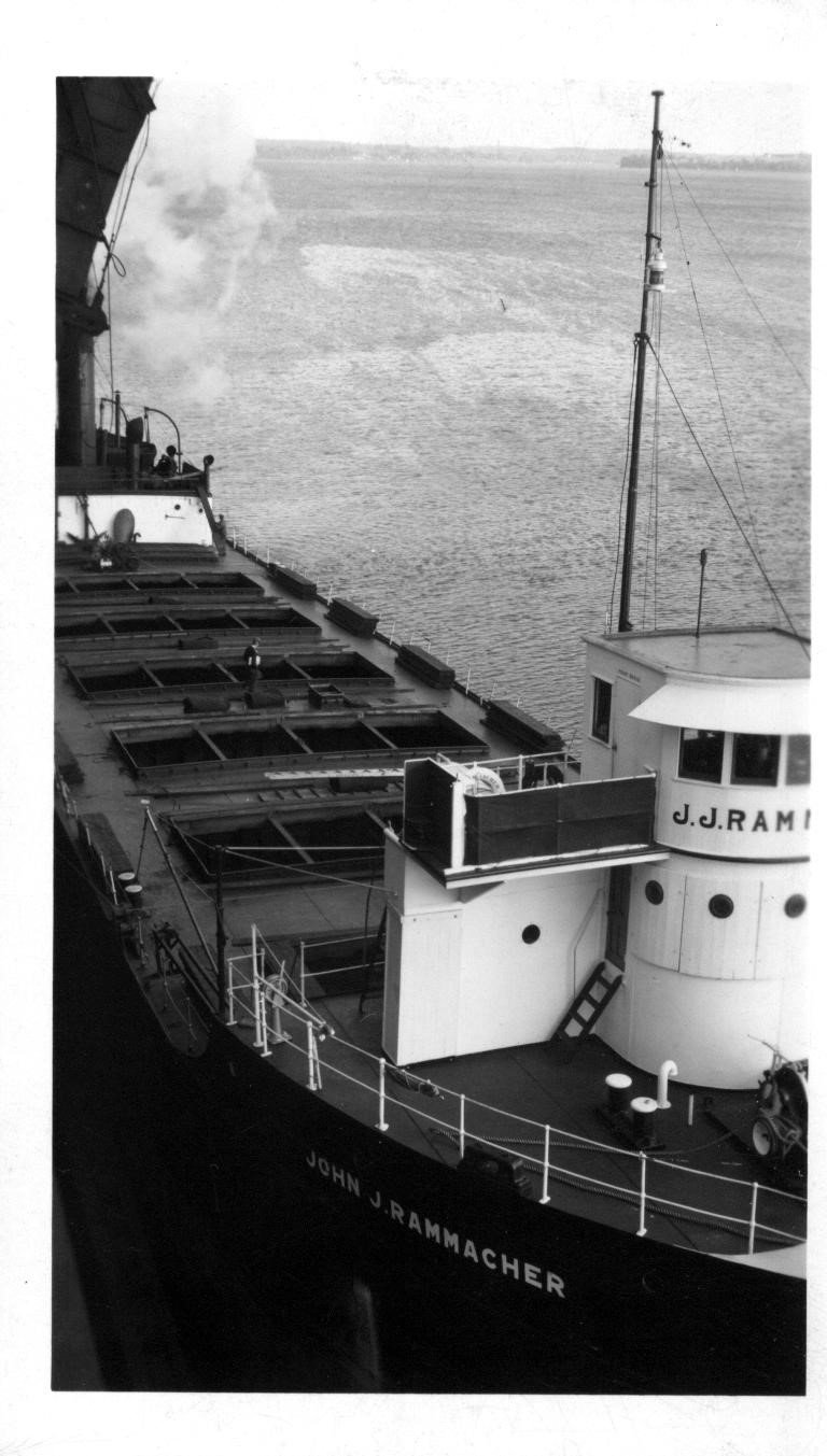 Freighter John J. Rammacher seen from above, hatches open, its name painted on the bow and pilothouse