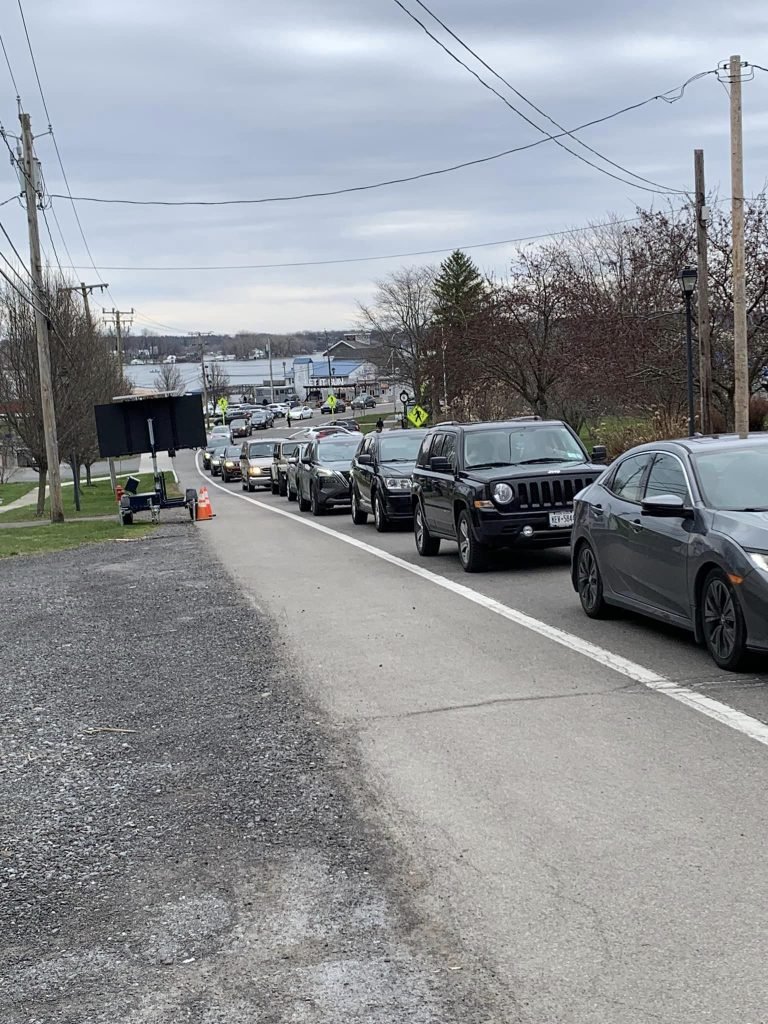 Long line of cars backed up along a village road as crowds leave