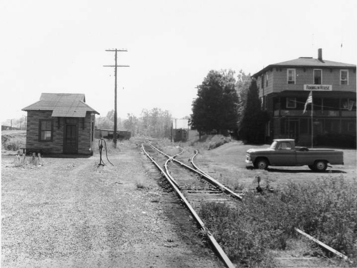 The Yardmaster's Office beside curving railroad tracks, and the two-story Franklin House with a pickup truck in front